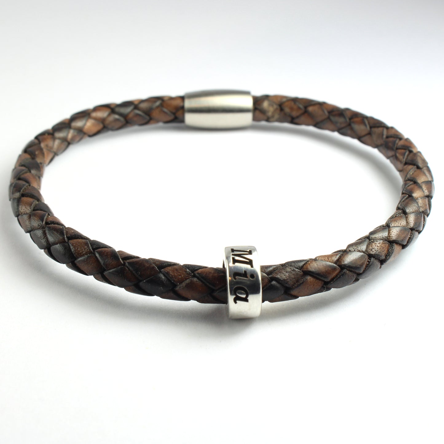 An antique brown genuine leather braided bracelet with 1 personalized sterling silver bead, on a white background