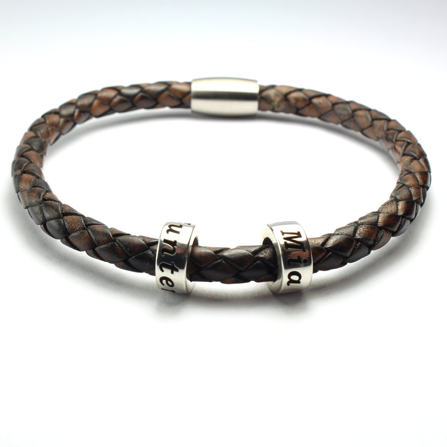 An antique brown genuine leather braided bracelet with 2 personalized sterling silver beads, on a white background