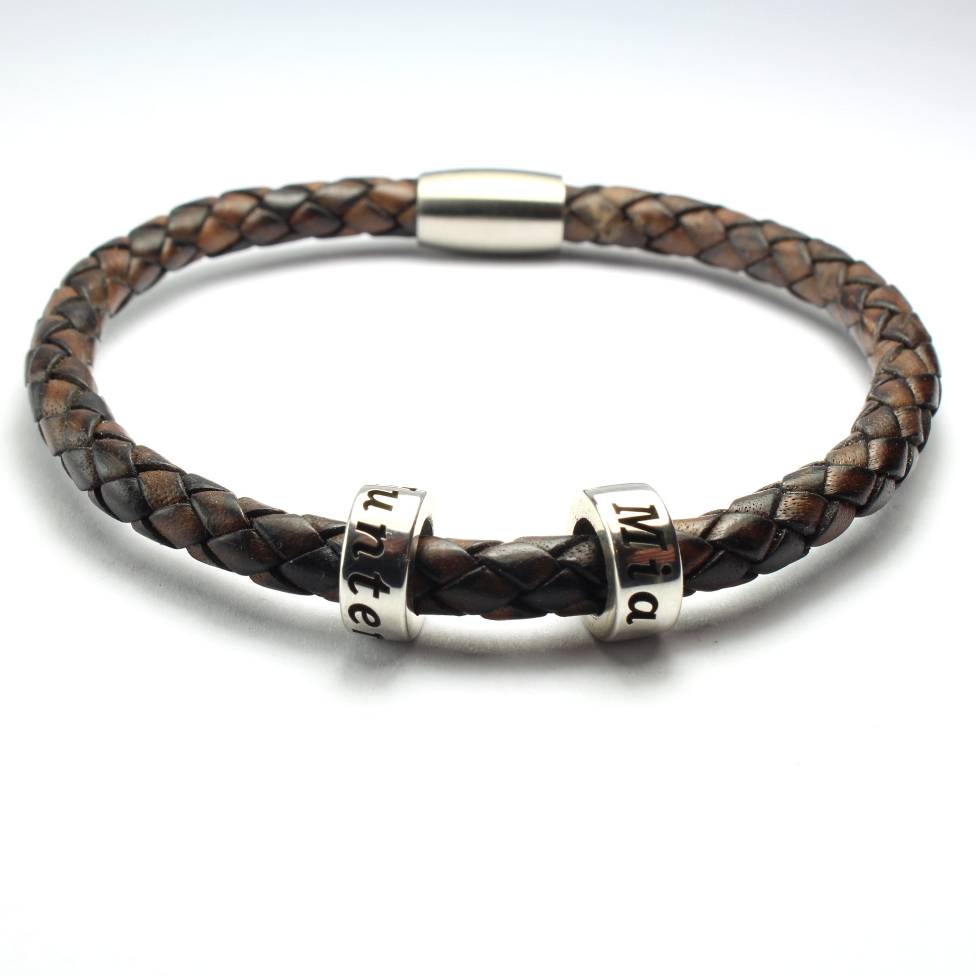 An antique brown genuine leather braided bracelet with 2 personalized sterling silver beads, on a white background
