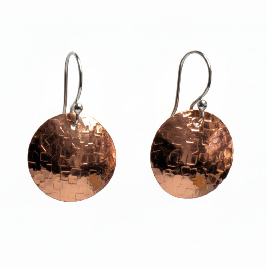 Copper textured disc earrings with a white background