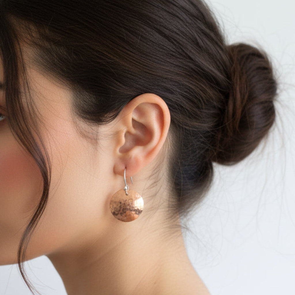 Woman wearing a copper earring with a plain white background