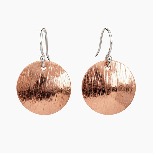 A pair of hammered copper disc drop earrings with silver French hook ear wires, displayed against a clean, light off-white background.