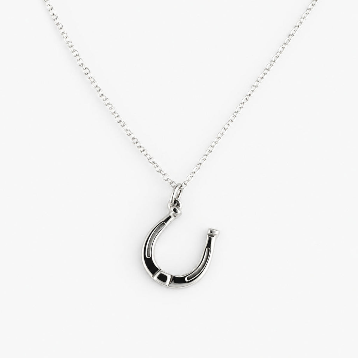 A silver horseshoe pendant necklace on a delicate silver chain, displayed against a light gray background.