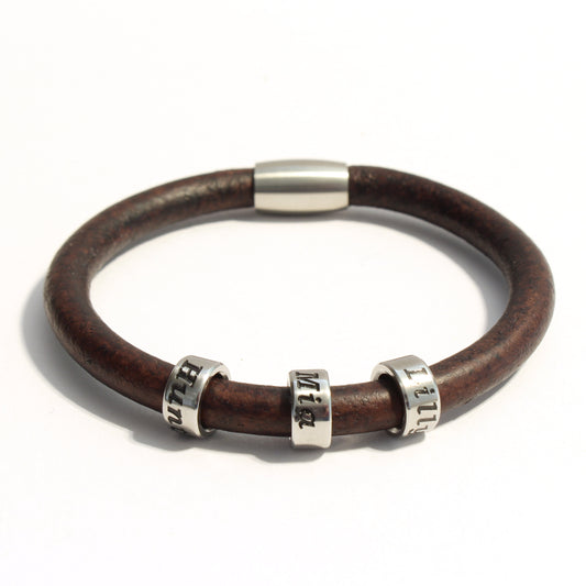 Brown leather bracelet with 3 stainless steel cylindrical beads on a white background