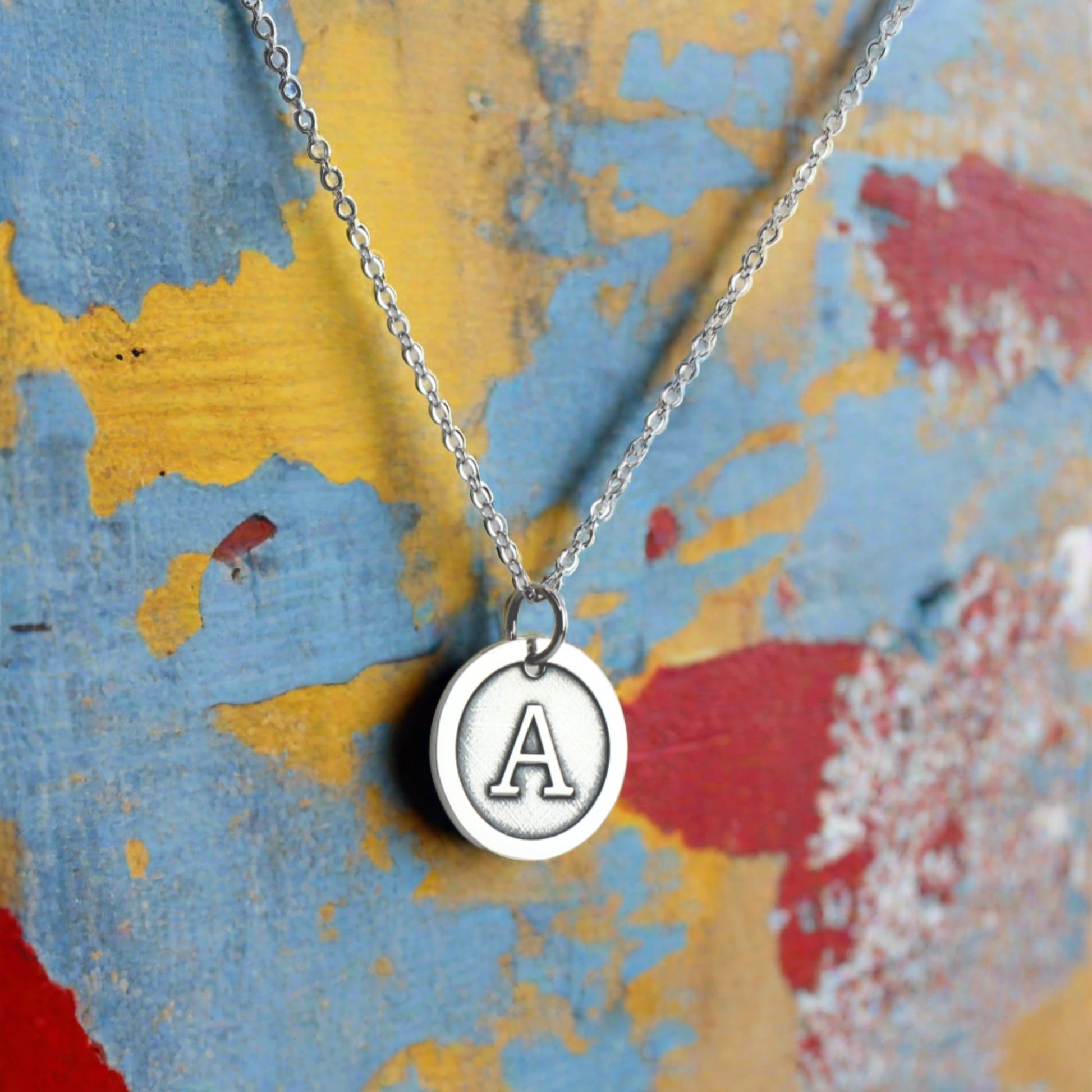 Sterling Silver Initial Necklace against a blue, yellow and red background