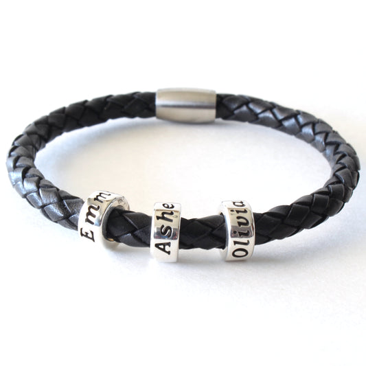 A black braided leather bracelet with 3 personalized sterling silver beads, on a white background.